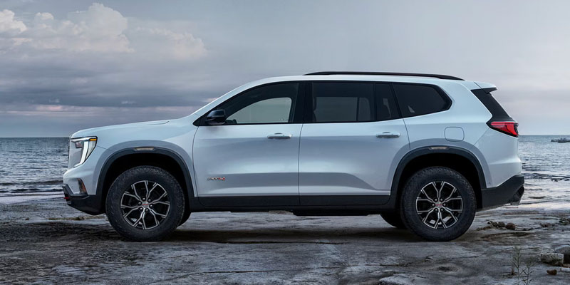 White GMC Acadia AT4 parked on a rocky shoreline.